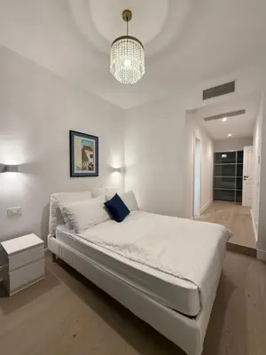 a white bedroom with a large bed and a chandelier at Vita Lux Vatican Suites in Rome