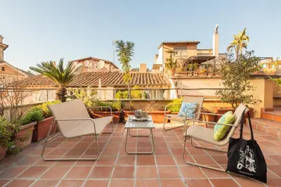 a patio with chairs and a table on a roof at Casa Maestro, a Burghesius home in Rome