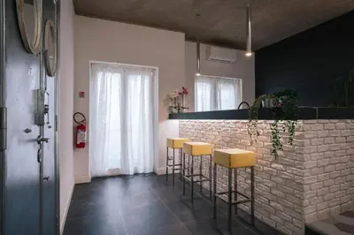 a kitchen with yellow stools and a brick wall at SuiteFrattini degli Eroi in Rome