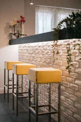 two yellow bar stools in front of a brick wall at SuiteFrattini degli Eroi in Rome