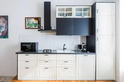 a kitchen with white cabinets and a black refrigerator at Blu Colombo in Rome
