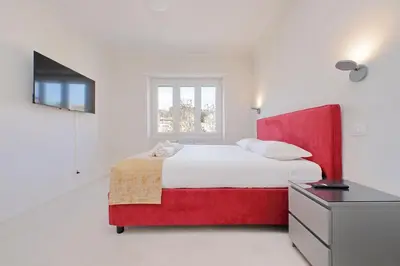 a large white bedroom with a red bed in it at 4BNB - Jacuzzi Trionfale Apartment in Rome