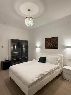 a white bedroom with a large bed and a chandelier at Vita Lux Vatican Suites in Rome