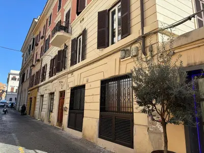 a building with black shutters on a narrow street at Luce suite trastevere in Rome
