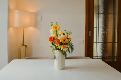 a white vase with a bouquet of flowers on a table at Attico Aurelia Antica in Rome