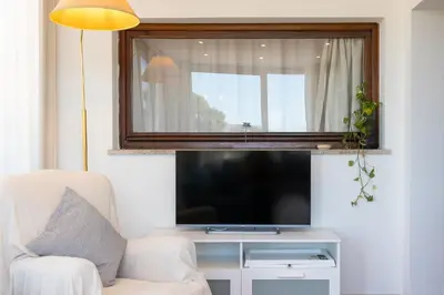 a living room with a television and a white chair at San Pancrazio Penthouse by Rental in Rome in Rome
