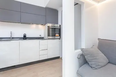 a kitchen with white cabinets and a gray couch at Rhome Vatican Chic in Rome
