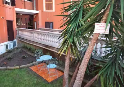 two chairs and a palm tree in front of a building at Casita in Rome