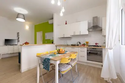 a kitchen with white cabinets and a table with yellow chairs at Roma Big terrace Home in Rome