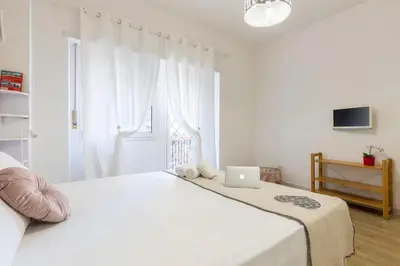a white bedroom with a bed with a laptop on it at Roma Big terrace Home in Rome