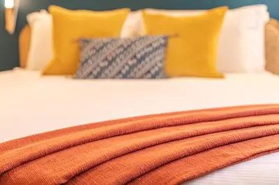 a bed with an orange blanket on it with pillows at YCH-Unique apartment near Vatican in Rome