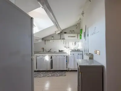 a kitchen with white cabinets and a large window at Central Rome Terrace Apartment in Rome
