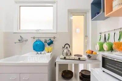a white kitchen with a sink and a mirror at Roma MetroB Apartment in Rome