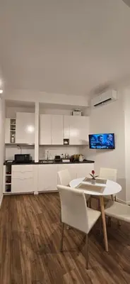 a kitchen with white cabinets and a table and chairs at Rooms And Comfort Apartment in Rome