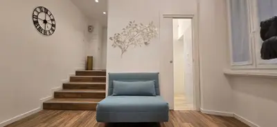 a room with a chair and a clock on the wall at Rooms And Comfort Apartment in Rome
