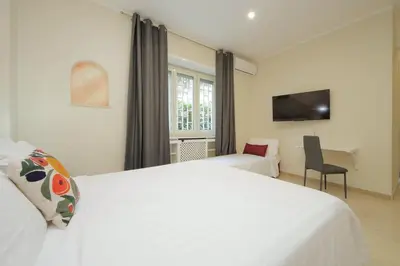 a bedroom with a large white bed and a chair at Vatican Rooms Mura Aurelie in Rome