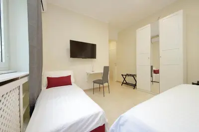 two beds in a room with a tv on the wall at Vatican Rooms Mura Aurelie in Rome