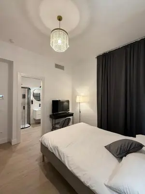 a bedroom with a bed and a television and a chandelier at Vita Lux Vatican Suites in Rome
