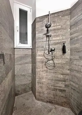 a shower in a bathroom with a stone wall at MaLoMA Home intero alloggio fronte metro A in Rome
