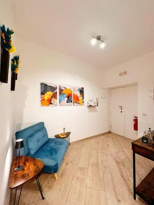 a living room with a blue couch and paintings on the wall at MaLoMA Home intero alloggio fronte metro A in Rome