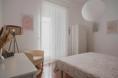a white bedroom with a bed and a chair at Casetta in Rome