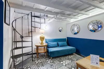 a living room with a blue couch and a spiral staircase at Vivilo Collection - Macelli Spanish Steps Apartment in Rome