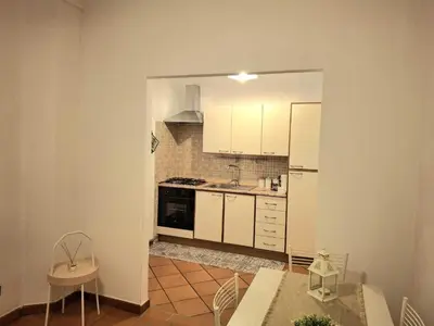 a kitchen with white cabinets and a table and chairs at Candia 66 at the Vatican Museums in Rome