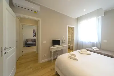 a white bedroom with a bed and a television at Palumbo 12 Holiday Home in Rome