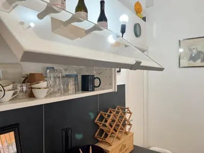 a kitchen with a shelf with bottles and wine glasses at Loft Lumineux à Trastevere in Rome
