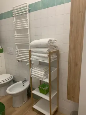a bathroom with a shelf with towels and a toilet at Numa House in Rome