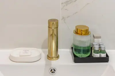 a sink with a faucet and a bottle of green liquid at La Piccola Luxury Suite in Rome