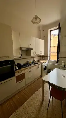 a kitchen with white cabinets and a table in it at Casa Domenica in Rome
