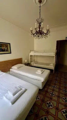two beds in a room with a chandelier at Casa Domenica in Rome