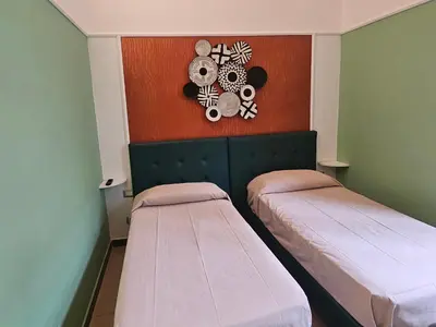 a room with two beds and a clock on the wall at San Lorenzo Accommodation One in Rome