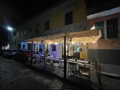 a table with chairs and an umbrella on a street at night at San Lorenzo Accommodation One in Rome