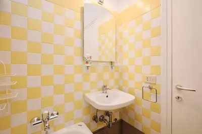 a yellow tiled bathroom with a sink and a mirror at Penthouse 5 minutes from the Vatican - 5 bedrooms & 4 bathrooms in Rome