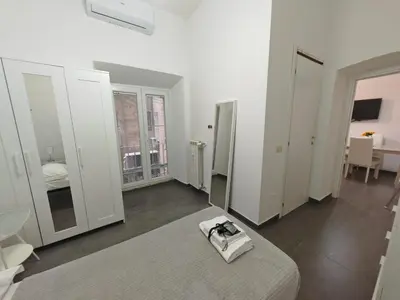 a white room with a bed and a mirror at Emilia's Dream Apartment in Rome