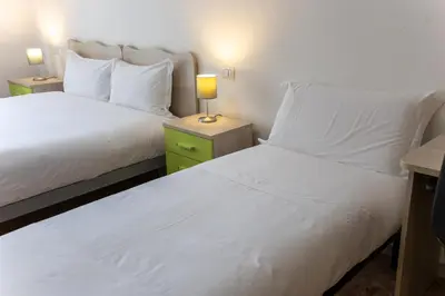 two beds in a room with white sheets and a lamp at Veturia in Rome