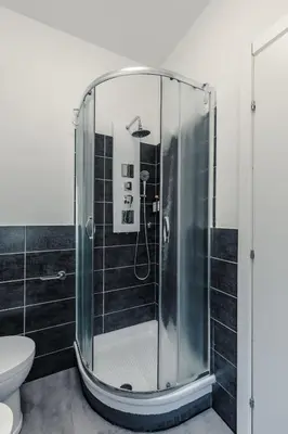a glass shower in a bathroom with black tiles at Veturia in Rome