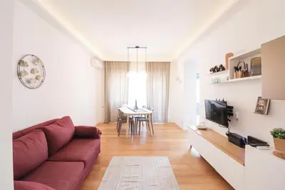 a living room with a red couch and a table at Elegant & Chic 2 Suites Apartment - 5min to Station, AC, Wi-Fi in Rome