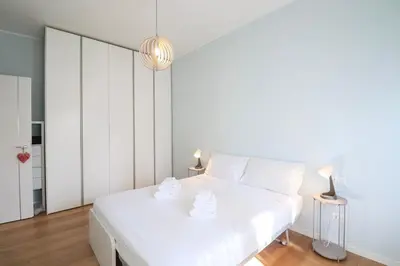 a white bedroom with a white bed and two lamps at Elegant & Chic 2 Suites Apartment - 5min to Station, AC, Wi-Fi in Rome