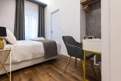 a bedroom with a bed and a desk and a chair at G MARCONI Rooms & Suites in Rome