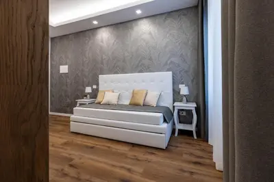 a bedroom with a white bed and a wall at G MARCONI Rooms & Suites in Rome