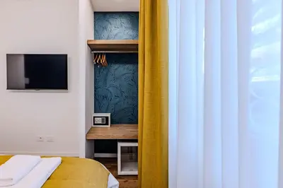 a bedroom with a bed and a yellow curtain at G MARCONI Rooms & Suites in Rome