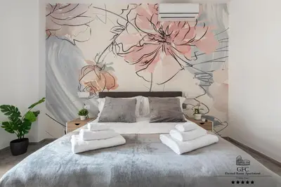a bedroom with a bed with a flower mural on the wall at GFC Eternal Rome Apartment - 5min to Tiburtina Station MetroB, 2 Bathrooms, Terrace, A-C in Rome