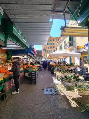 a market with people standing in a market with fruits and vegetables at Casa del Vinile Roma in Rome