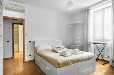 a white bedroom with a bed and a desk at Colosseum Monti large flat in Rome