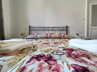 a large bed with a floral bedspread on it at Romein5minutes in Rome