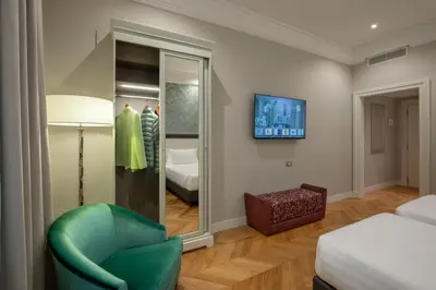 a room with a green chair and a mirror at Rose Garden Palace Roma by OMNIA hotels in Rome