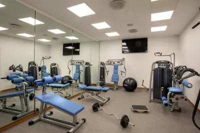 a gym with blue chairs and a large mirror at Rose Garden Palace Roma by OMNIA hotels in Rome